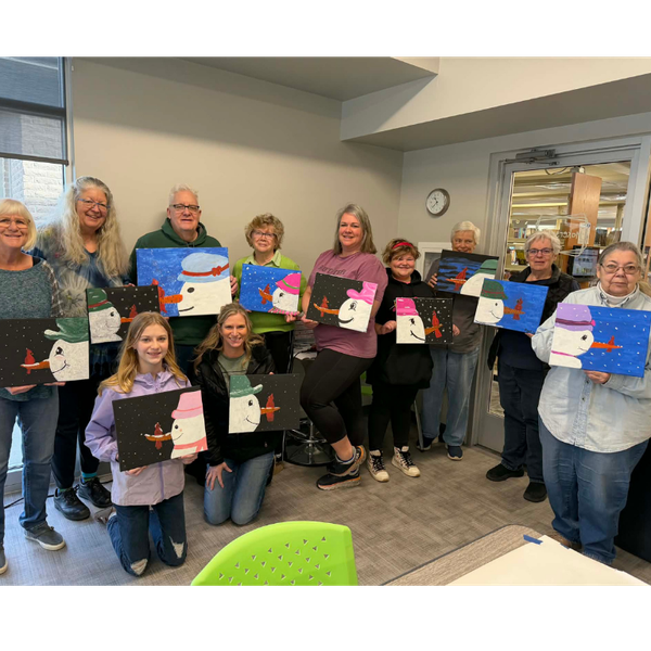 a group of people holding paintings of snowmen with different colors and attire