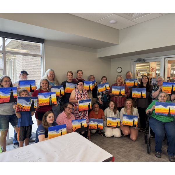 a group of people holding their sunset lighthouse paintings