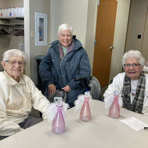 Three seniors sitting at a table with glass angels in front of them